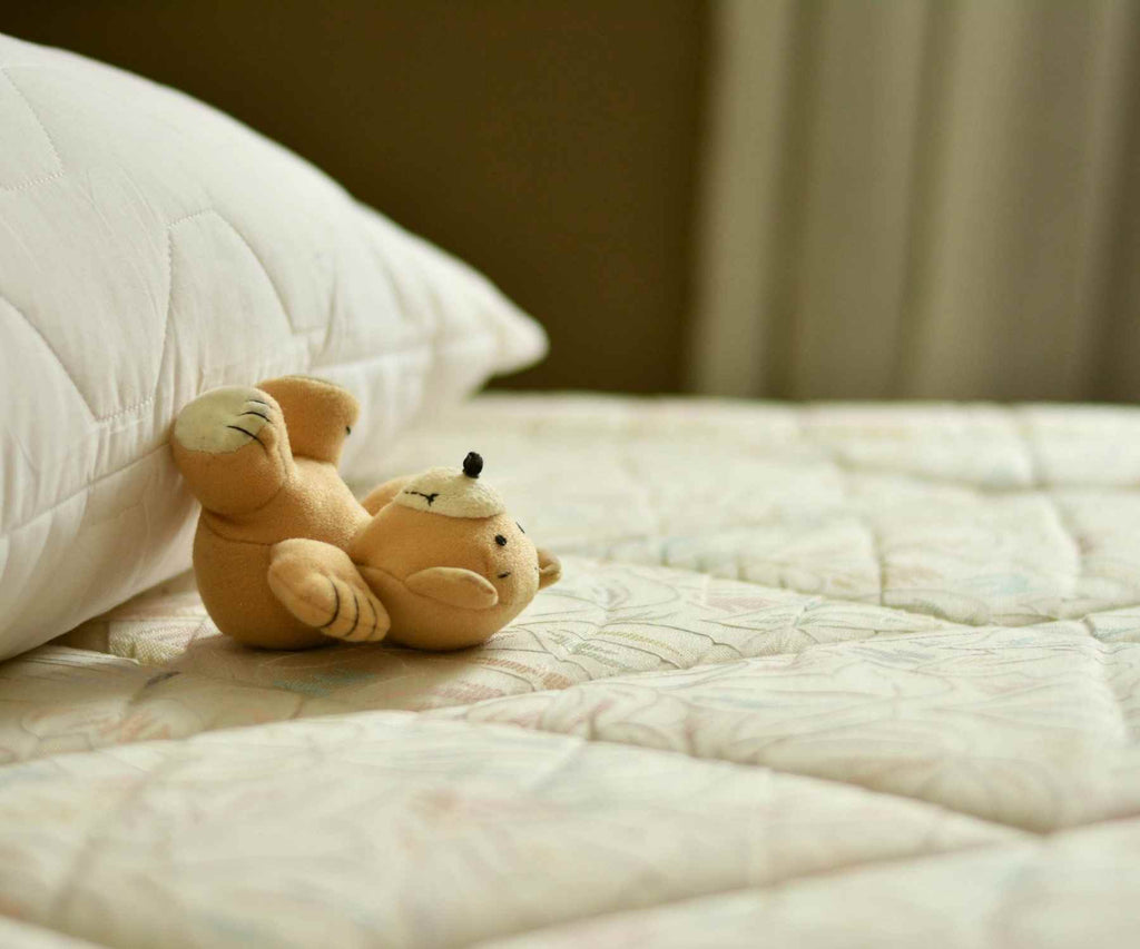 Close up of mattress with small teddy bear and pillow