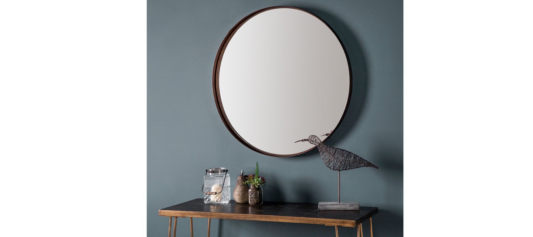 Round wall mirror on blue wall above a console table
