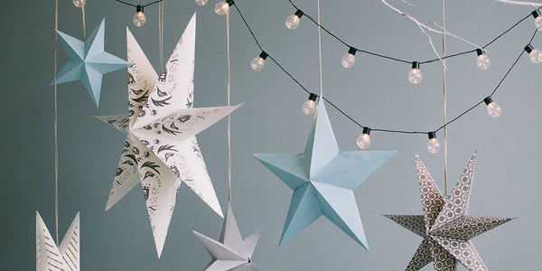 Several hanging paper stars with a string of lights