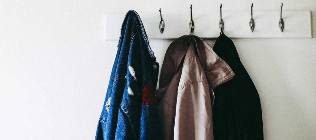 Denim jacket and other coats hanging on row of hooks