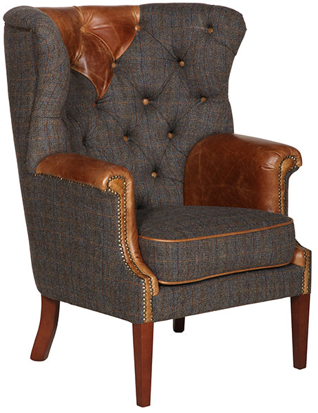 A dark grey wingback armchair with brown leather details