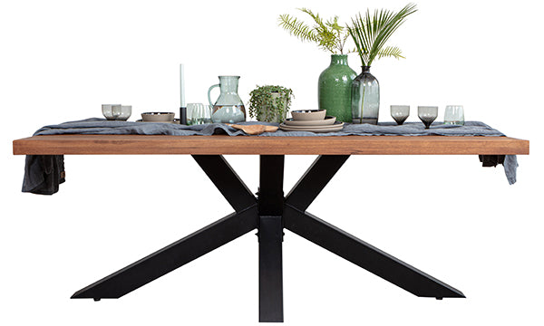 Industrial style dining table with a black steel spider leg, linen and ceramics on top