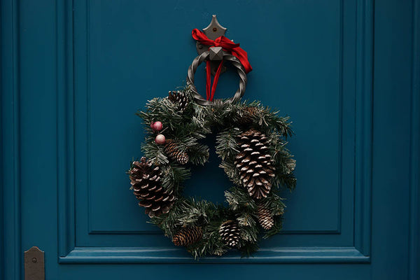 A Christmas wreath hanging on a dark blue front door