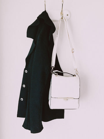 Black coat hanging on hook with white bag