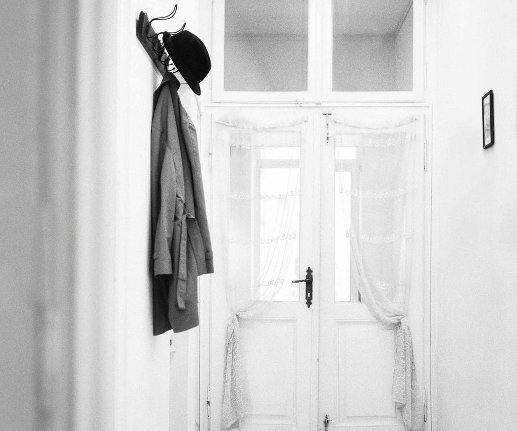White hallway with grey coat and hat hanging on hooks