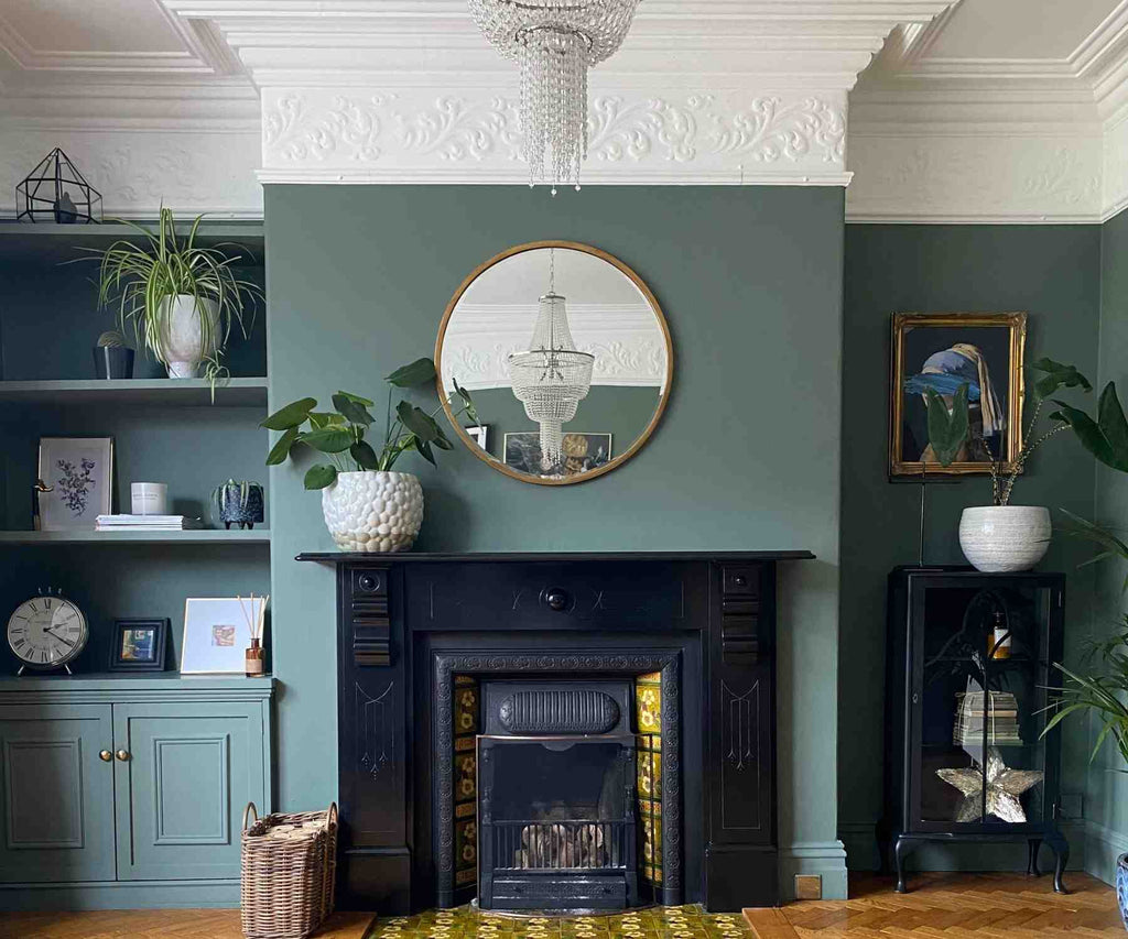 Victorian fireplace with dark grey walls and round wall mirror