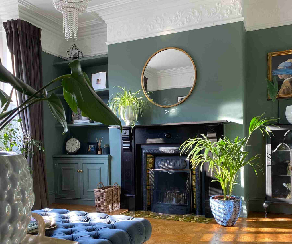Dark living room with green plants and blue footstool