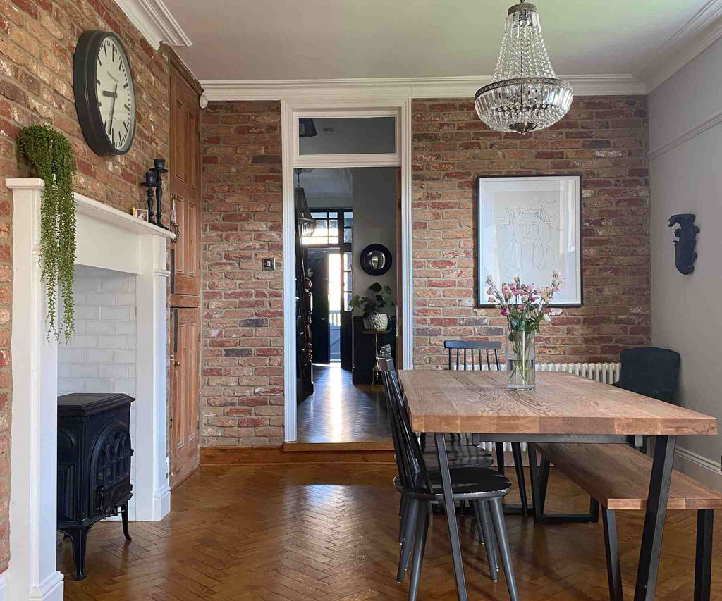 Dining area with industrial dining table, brick wall and white fireplace