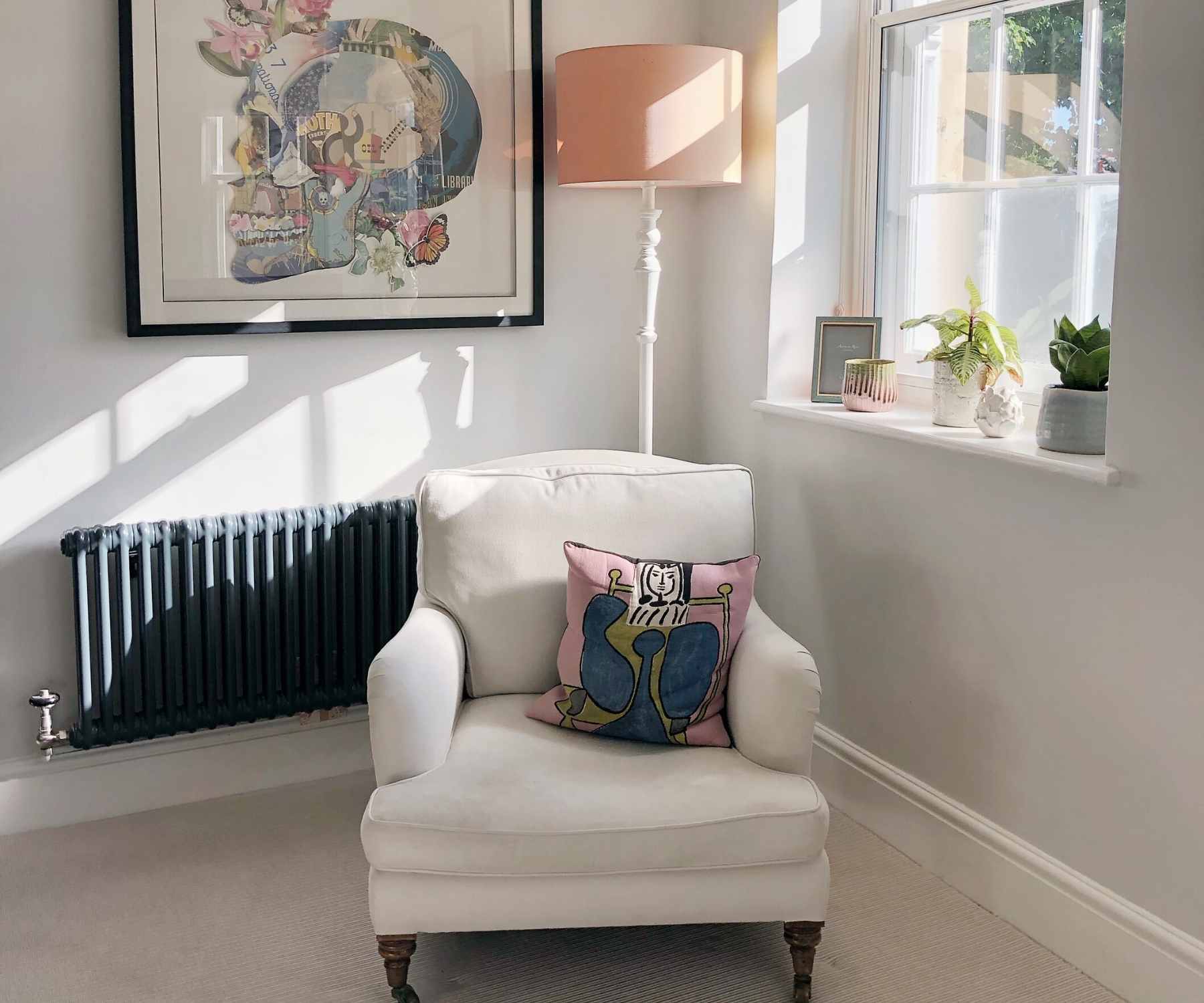 White armchair next to sunny window with skull wall art