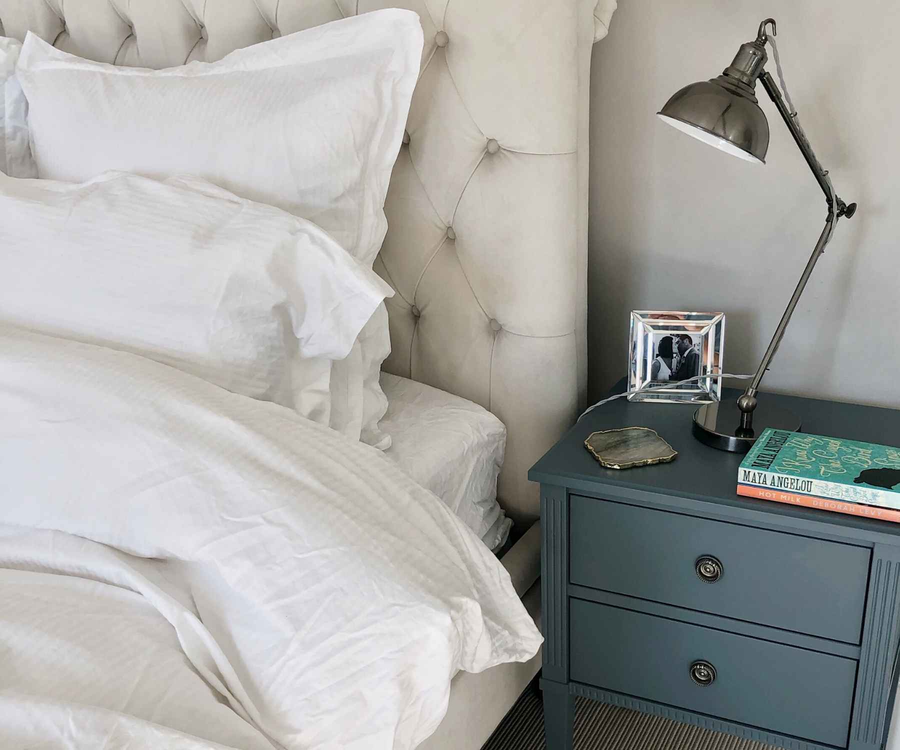 Blue bedside table with lamp next to white king size bed