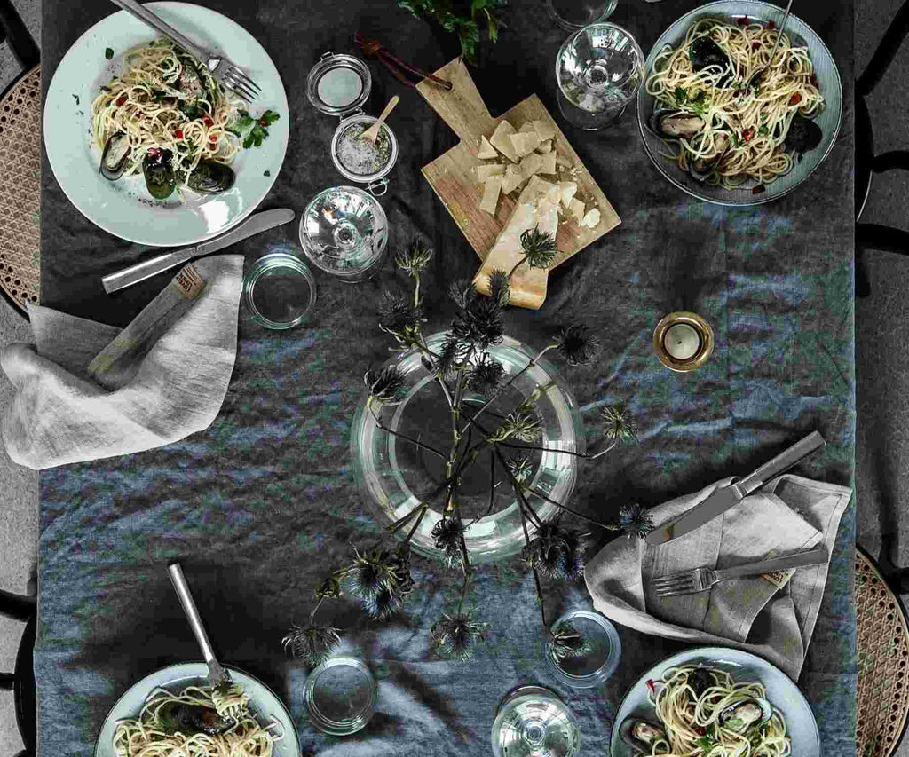 Flat lay image of dining table with grey tablecloth and various food dishes