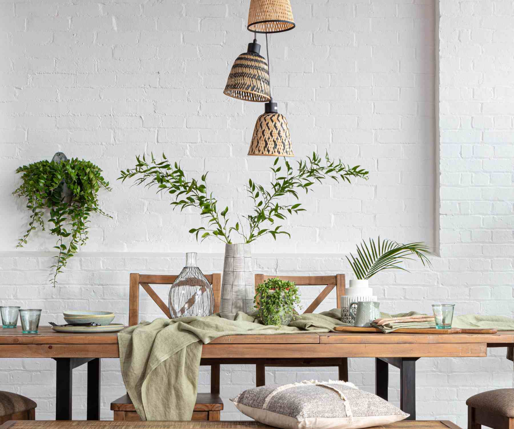 Green plants on reclaimed wood dining table and on white brick wall