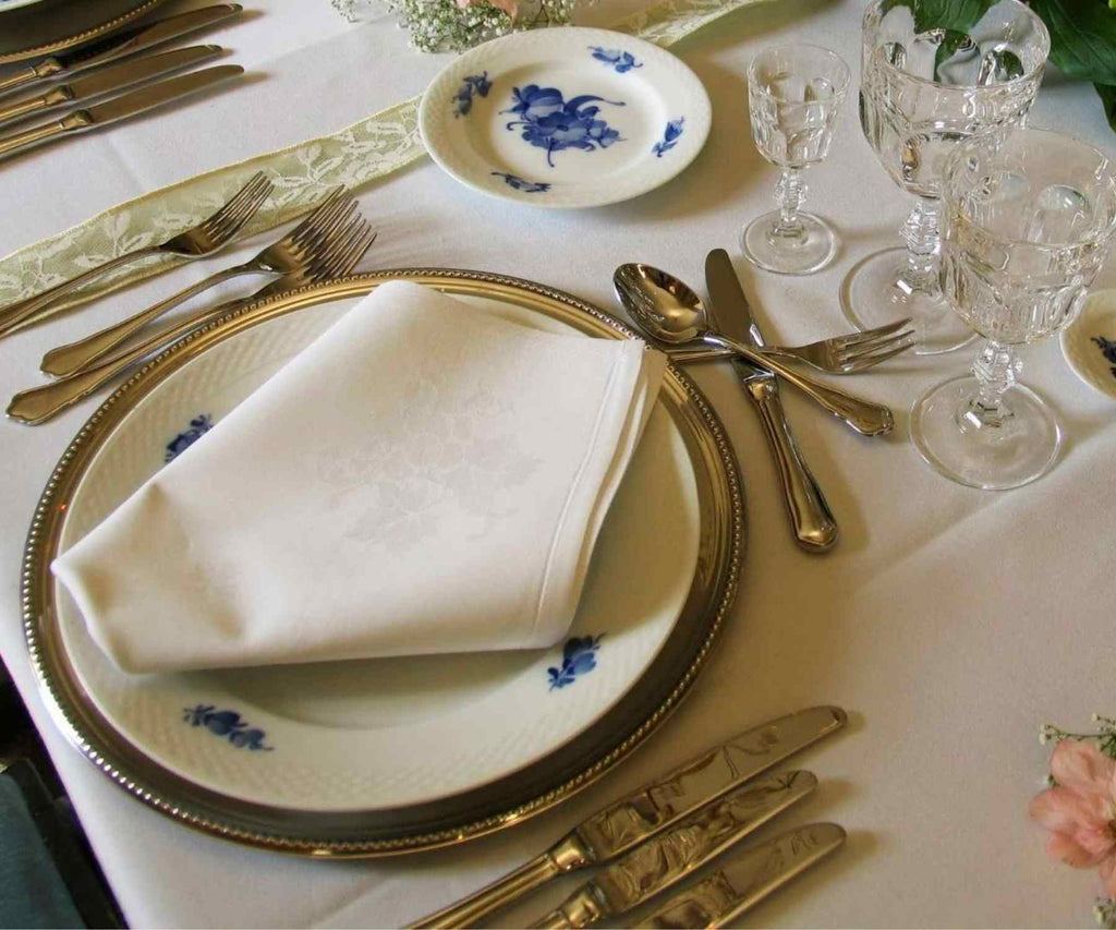 White folded napkin on table with white tablecloth and crockery