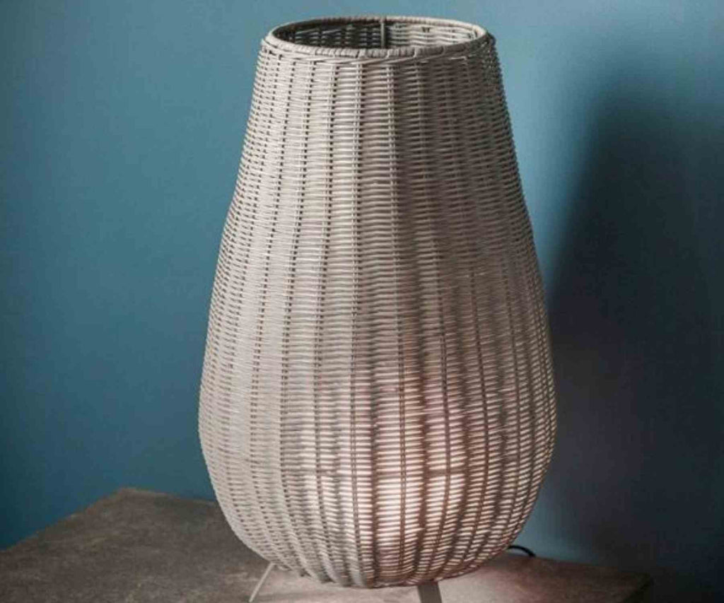 Grey wicker table lamp against blue wall