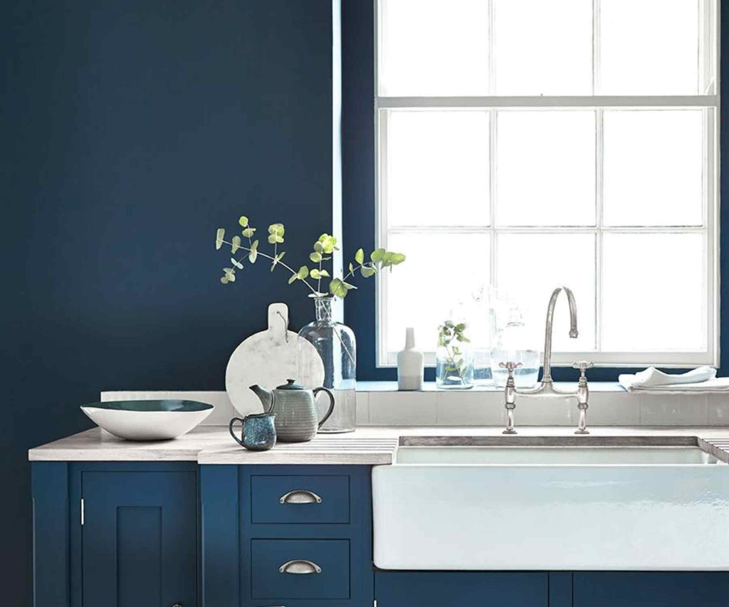 Dark blue painted wall and kitchen unit with white belfast sink