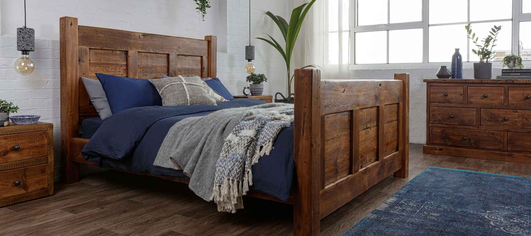 Reclaimed wood bed frame with blue bed covers and blue rug
