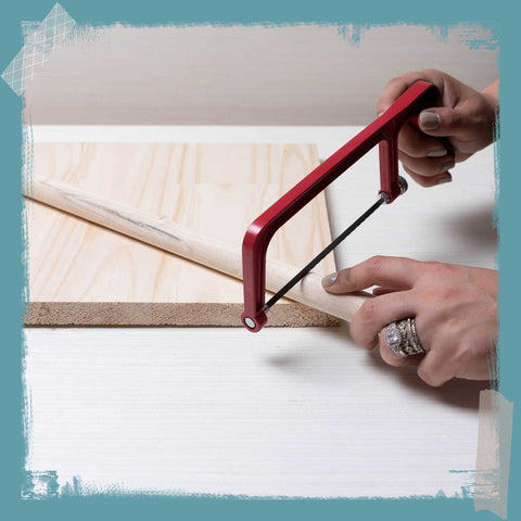 Two hands sawing a wooden dowel. 