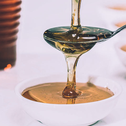 Honey being poured onto a spoon over a small dish.