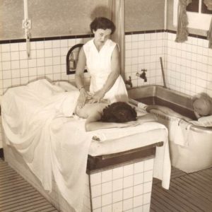 A woman gives another woman a massage in a treatment room.