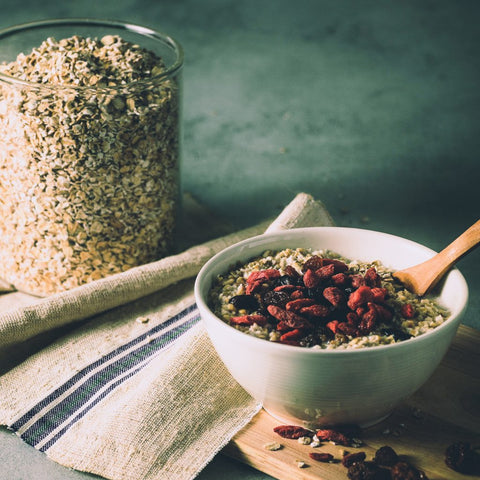 Bowl of oatmeal with toppings next to a kitchen towel and jar of dried oatmeal.