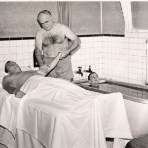 A man giving another man an arm massage. 