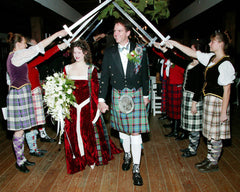 A bridal procession featuring kilts and a red celtic knot trimmed wedding dress