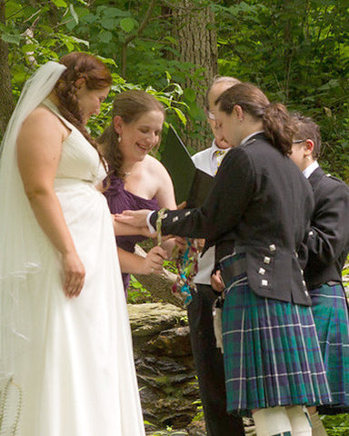 A bridesmaid ties one of the cords during a handfasting