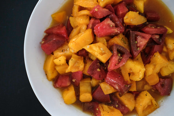 Marinated orange and red heirloom tomatoes in a bowl