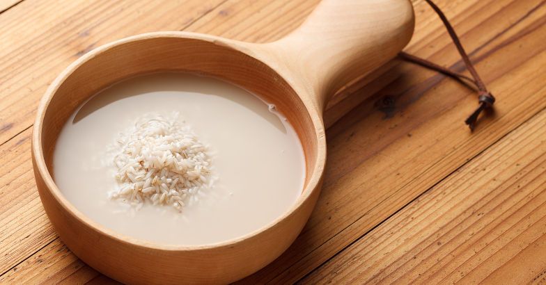 Rice and rice water in a wooden bowl on a wooden table