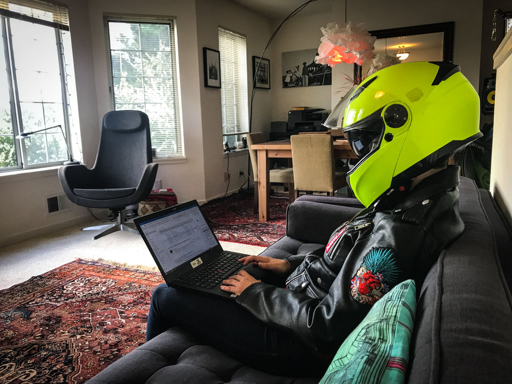 motorcyclist confined at home because of Covid wearing a helmet on laptop