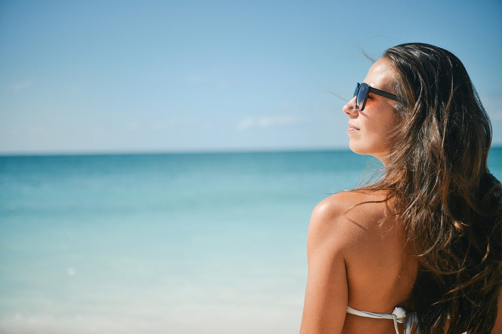 A woman wearing a polarize glasses on the beach sand