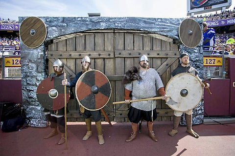 Viking reenactors at a Vikings Game with some A&A shields in the background.