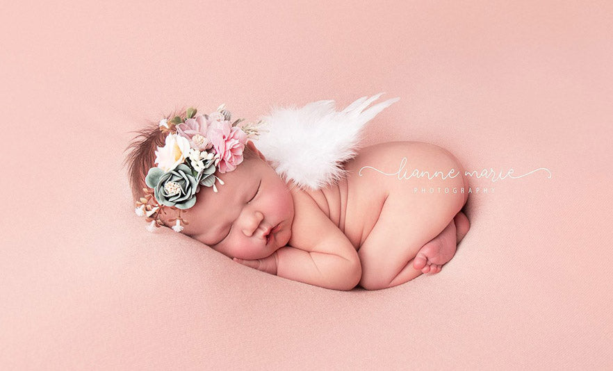 Image of tiny sleeping baby dressed as cherub with spring flower headband