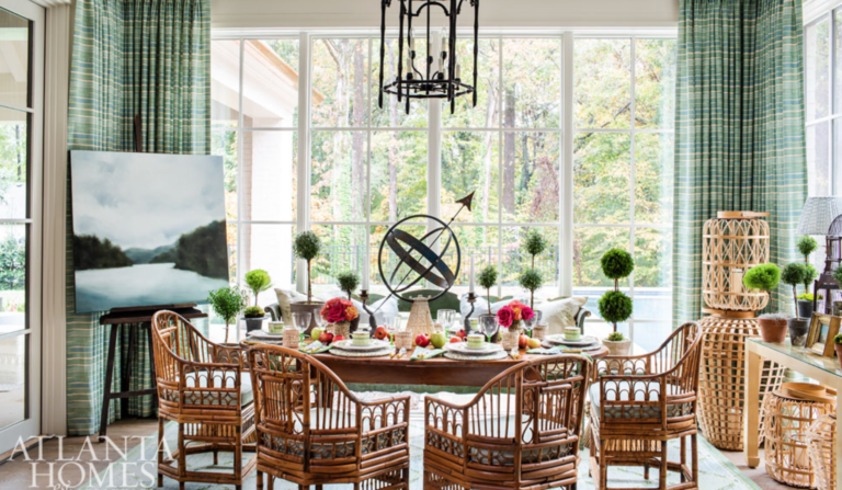 Rattan is hot! <a href="https://www.margaretkirklandinteriors.com/" target="_blank">Margaret Kirkland</a> adds a liberal dose of it here in the breakfast room and then tempers it with a serene landscape by Andrea Costa and plenty of green topiaries.