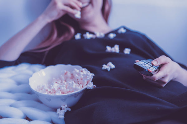Muchacha recostada comiendo popcorn mientras mira TV - Foto de Jetshoot