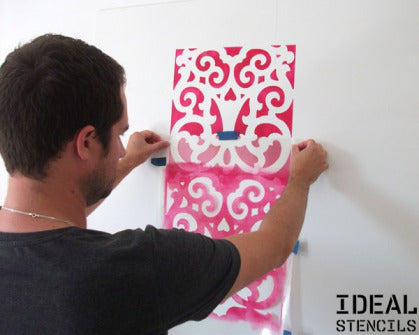 positioning a Moroccan style stencil on wall before painting