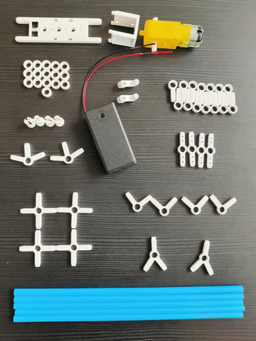 layout of blue straw, white plastic connectors, AA battery case and DC motor on a black table background