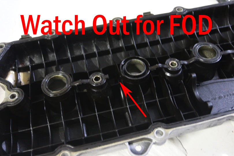 Underside of valve cover with piece of gasket missing. Text reads "Watch out for FOD".