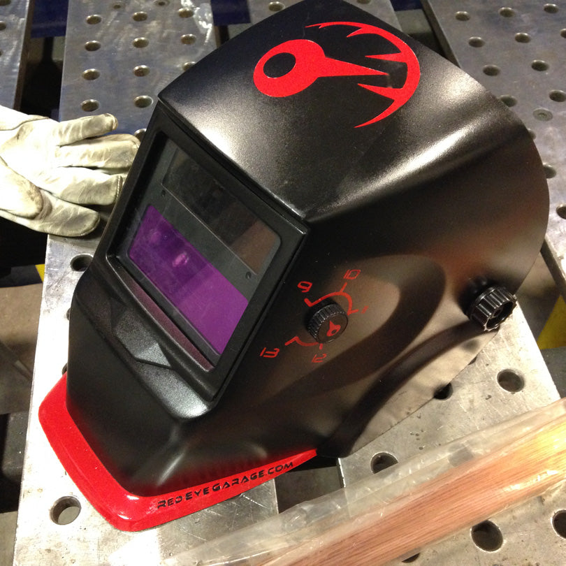 Custom painted welding helmet on a welding table.