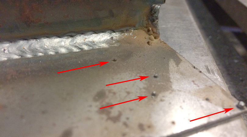 Weld splatter on a MIG weld. Tiny balls of metal are fused to the metal.