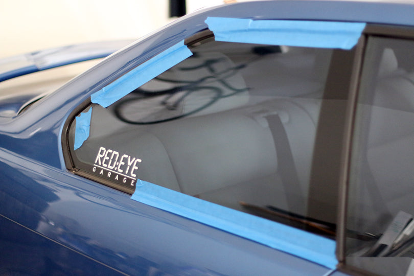 Rear side window taped to the exterior of the car with blue painter's tape.