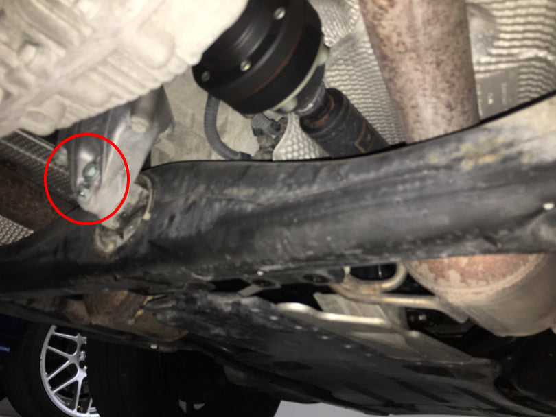 2 transmission mount bolts to be removed are circled in red.
