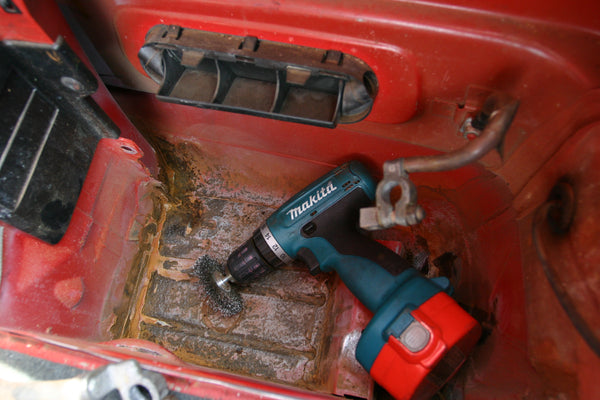 Rusty battery compartment with drill loaded with a wire brush.