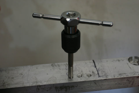 Tapping tool in hole in aluminum bar stock.