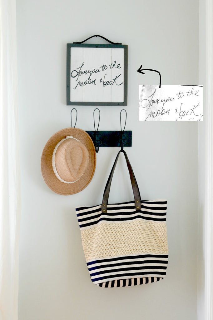 Handwriting memory sign on wood "Love you to the moon and back" hanging above coat rack with hat and bag