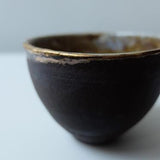 Stunning dark ceramic tea bowl with gold accents