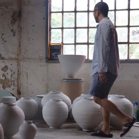 Kiho Kang in studio surrounded by ceramic vases 