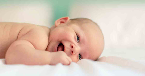 Happy baby laying down on bed laughing