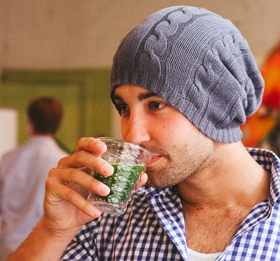 Guy with a beanie drinking matcha tea that he made with an electric whisk