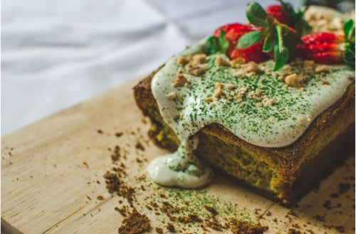 Matcha vanilla frosting green tea cake topped with strawberries and dusted with matcha powder